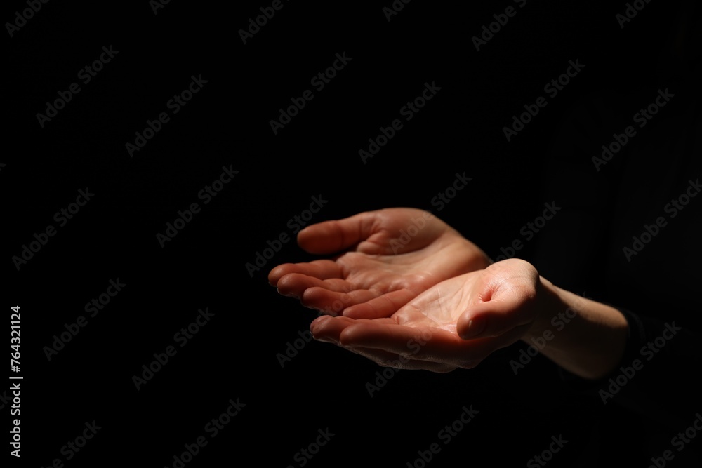 Religion. Woman with open palms praying on black background, closeup. Space for text Religion. Woman with open palms praying on black background, closeup. Space for text