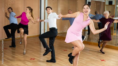 young smiling girl dancing jive with her partner in latin dance class