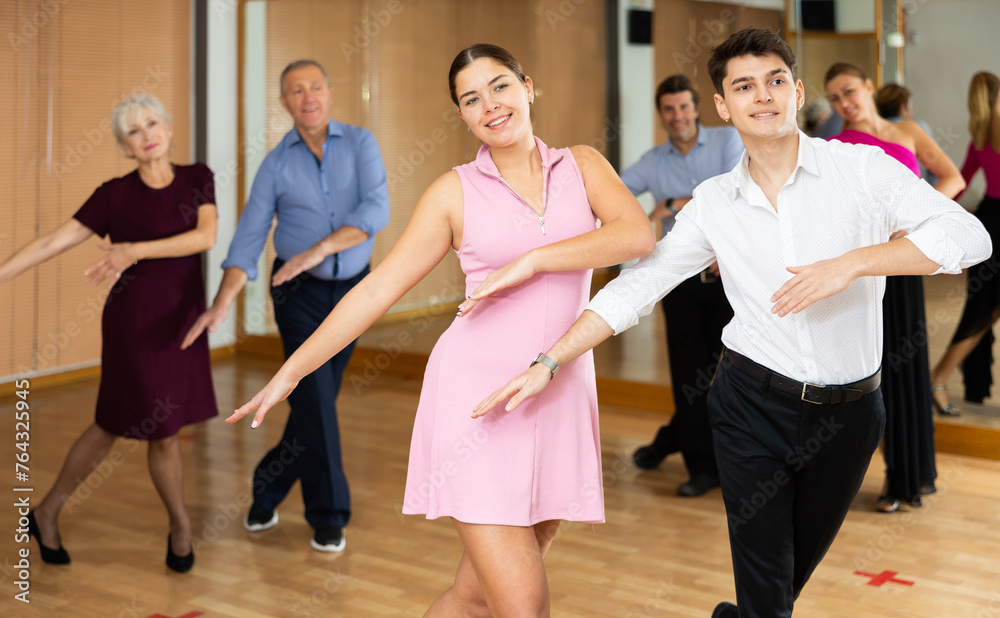 Fototapeta premium Dynamic young pair engaging in Latino dance in dance studio. Pairs training ballroom dance in hall