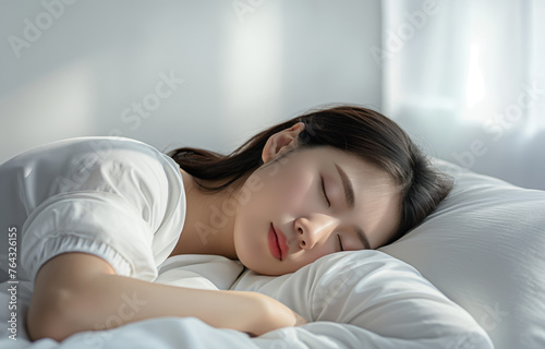 Asian woman peacefully sleeping on a bed with white sheets.