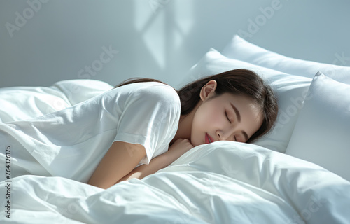 Asian woman peacefully sleeping on a bed with white sheets. © Koray