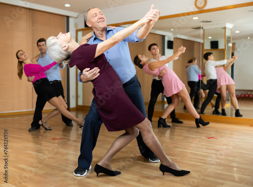 Happy older couple performing a paired ballroom dance in ballroom