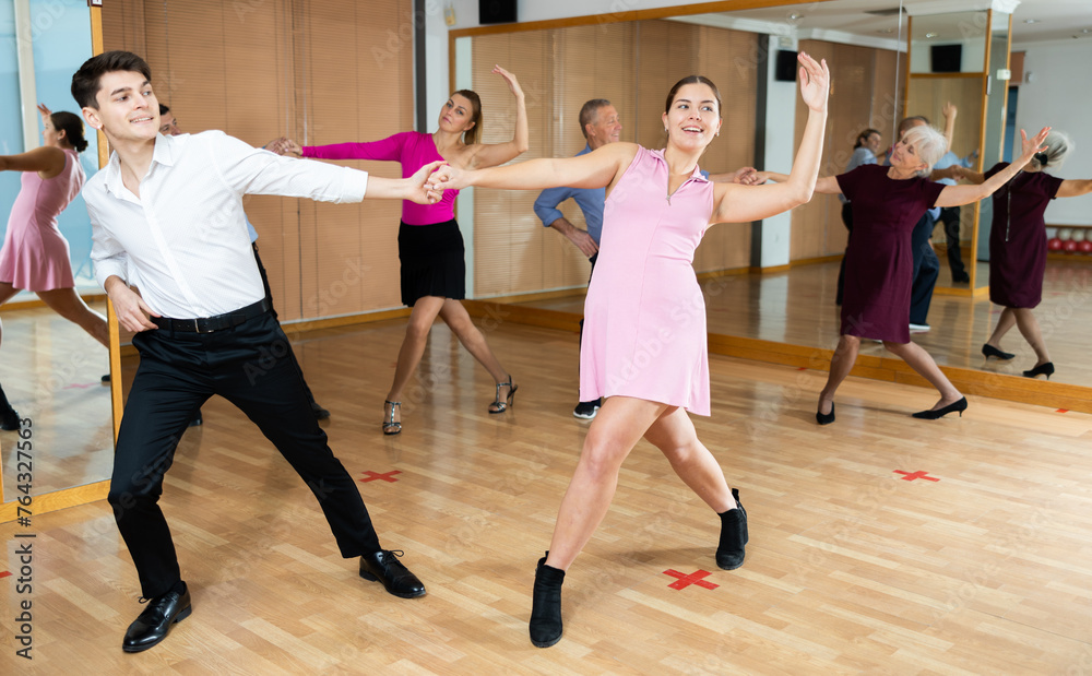 Dynamic young pair engaging in ballroom dance in dance studio. Pairs training ballroom dance in hall