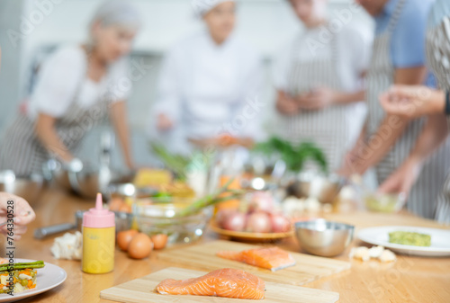 Row piece of salmon on wooden cutting board against blurred background of kitchen table of cooking classes