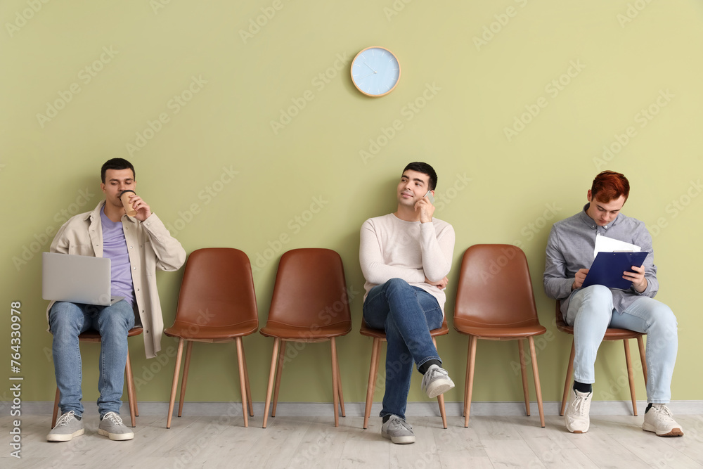 Obraz premium Male applicants waiting for job interview near green wall in room