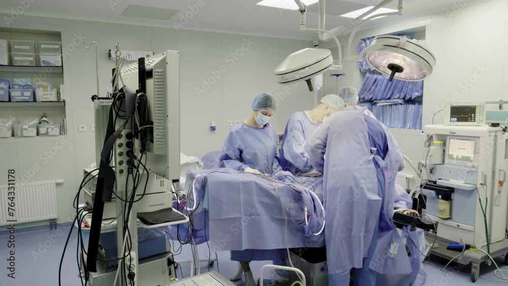 A group of professional mixed race surgeons in uniform performing an operation in the operating room using medical instruments. A group of professional mixed race surgeons in uniform performing an operation in the operating room using medical instruments.