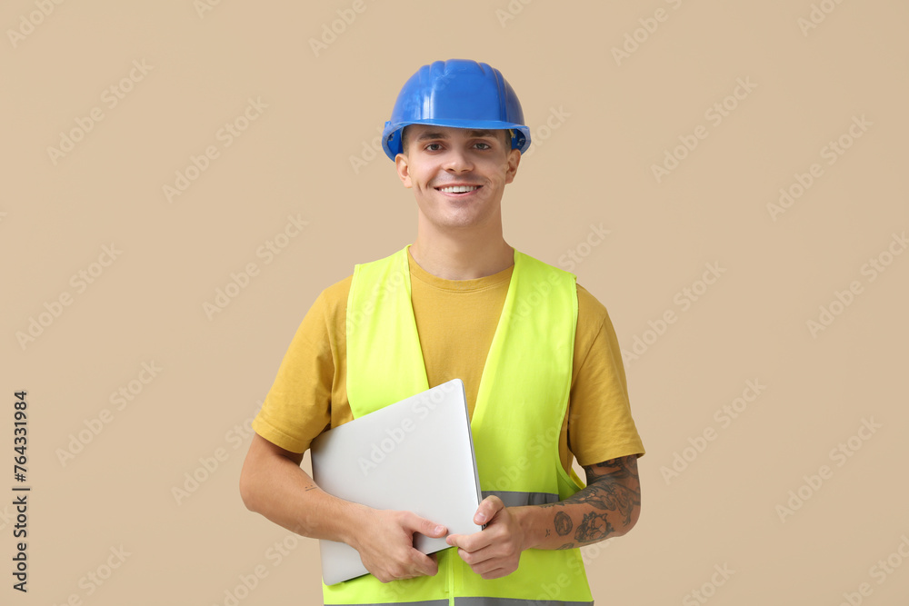 Young male engineer with laptop on beige background Young male engineer with laptop on beige background