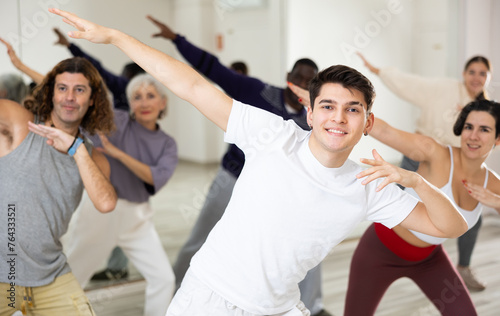 Emotional young guy enjoying active dancing during group training in dance studio..