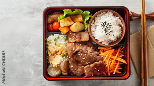 Asian bento box with meat, rice, and vegetables on the side. The food is presented in a red square container that has been placed against a grey background