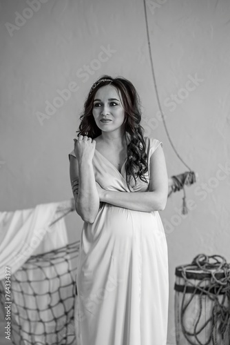 Portrait of a beautiful pregnant woman in a white dress. Black and white photo.
