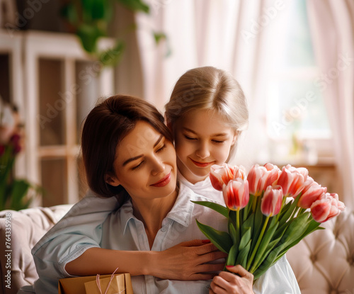 Woman holding bouquet of flowers next to little girl on couch.