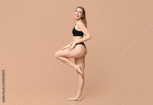 Sexy young woman in black cotton underwear on beige background