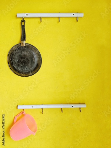 Obraz na płótnie A hanger for storing cooking utensils attached to the wall with a yellow backgro