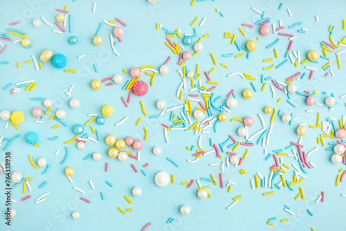 Sweet colorful sprinkles scattered on blue background