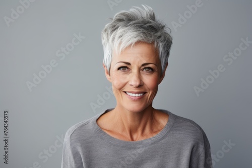Portrait of a happy mature woman with grey hair against grey background
