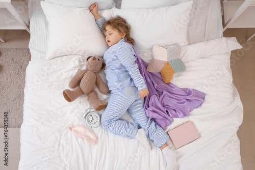 Foto Sleeping little girl dreaming of super powers in bed