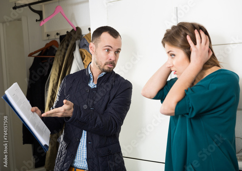 Fotografi Portrait of young frustrated woman talking to debt collector visiting her at hom