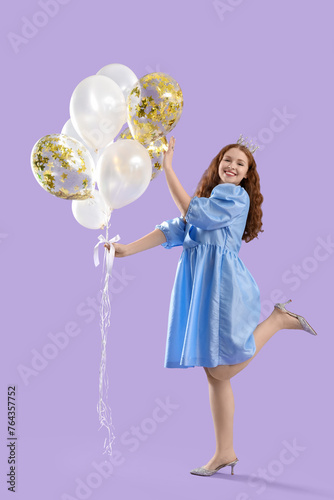 Young redhead woman in crown with balloons on lilac background