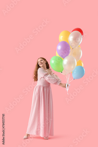 Young woman with balloons on pink background