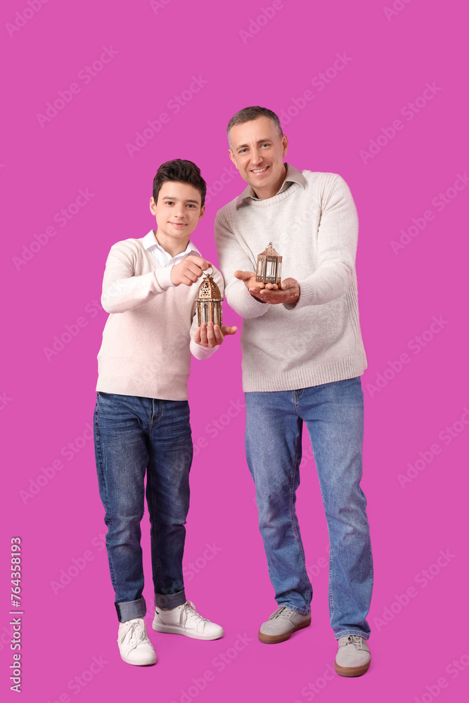 Happy Muslim father and his son with fanoos on pink background. Eid al-Fitr celebration Happy Muslim father and his son with fanoos on pink background. Eid al-Fitr celebration