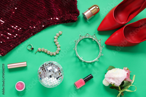 Female prom outfit with disco ball, boutonniere and makeup products on green background