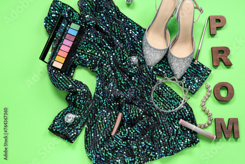 Word PROM with dress, shoes and eyeshadows on green background