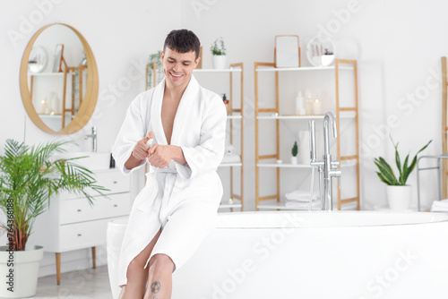 Young man applying cream on...