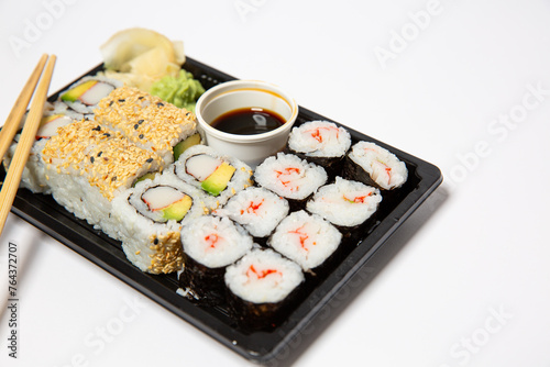 Sushi to go in a black takeaway box with wooden chopsticks on white background