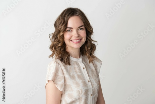 A woman with long brown hair is smiling and wearing a white shirt