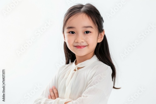 A young girl with long hair and white shirt is smiling for the camera