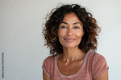 A woman with brown hair and a pink shirt is smiling