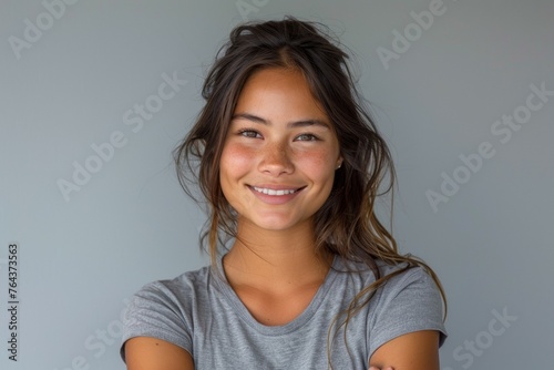 A woman with long brown hair and a gray shirt is smiling