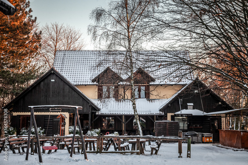 Selective blur on a mountain restaurant and bar, typical aline, with snow covered buildings and roofs in winter, during a cold sunset, surrounded by a forest, in a remote place. photo