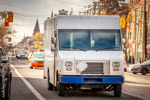 Selective blur on a white delivery van, in a typical north american street, getting ready for mail, packages and parcel delivery in a logistic service in Canada.