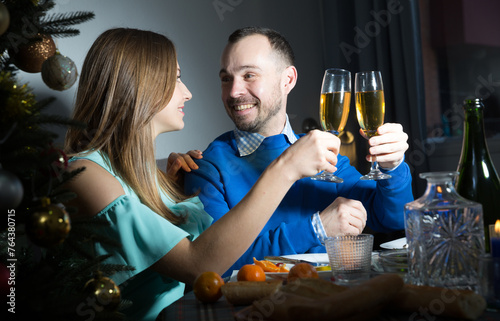Cheerful man and woman at dining table at Christmas night enjoying festive dinner