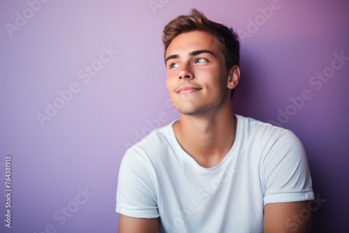 Portrait of a handsome young man looking up against purple background. © Iigo