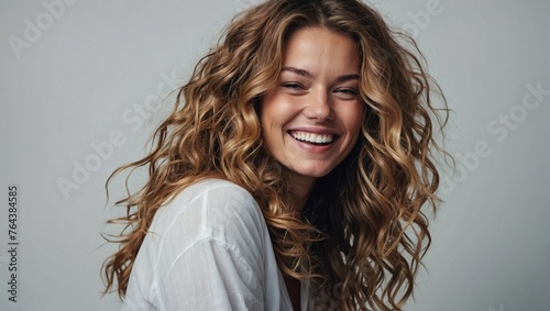 Dutch woman in her 20s with beautiful wavy hair posing smilingly on a white background, studio shot, space for advertising photo