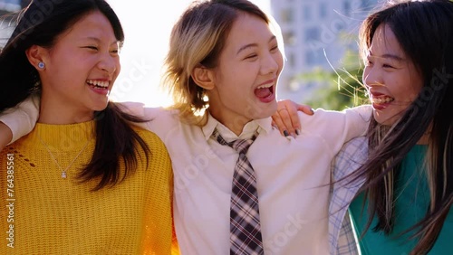 Cheerful Asian nice women friends walking carefree through city pointing to something in sky. Young happy Chinese female stroll embraced talking and laughing enjoying together spring sunny day outdoor photo