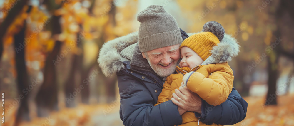 Homem mais velho abraçando seu neto no parque em pleno outono - obrazy, fototapety, plakaty 