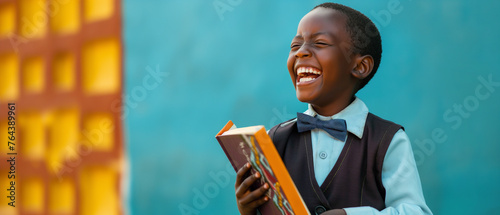 Garoto afro segurando um livro e dando risada 