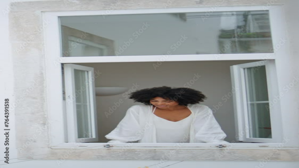 Domestic girl peeping window morning indoors. African lady relaxing vertical