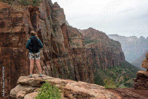 Woman Stands On Rock Outcropping And Looks Out Over Zion Canyon © kellyvandellen