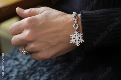 Close-up of a woman's wrist adorned with a silver snowflake charm bracelet.