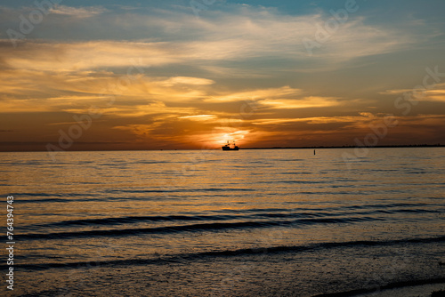 Sailboat sunset fantasy with a silhouetted boat sailing along its journey against a vivid colorful sunset