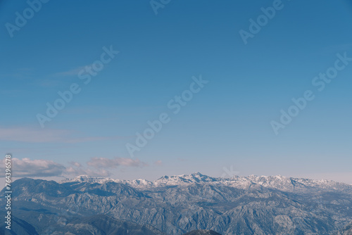 Snow-covered mountain range above the Bay of Kotor against the blue sky in winter. Montenegro
