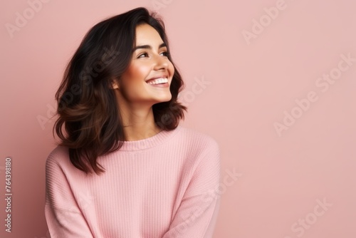 Portrait of happy smiling young woman in pink sweater, over pink background