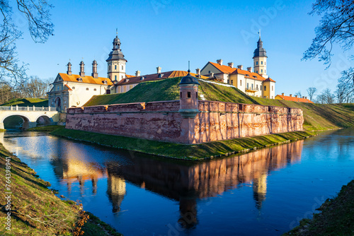Winter view of belarusian medieval Nesvizh Castle with park and ponds on sunny day photo