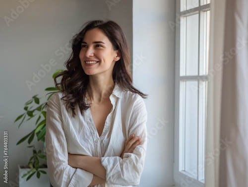 Happy, prosperous, gorgeous, and successful businesswoman dressed casually, posing in an office apartment, smiling, laughing, and crossing her hands. 