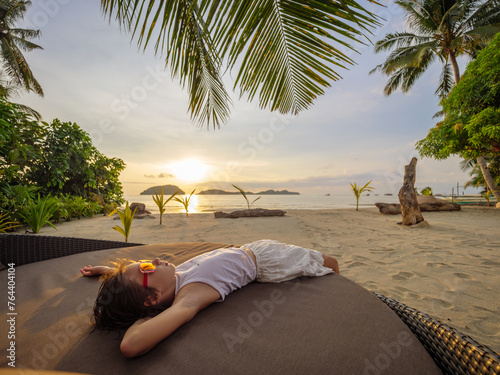 beautiful sunset on the beach. The child lies under the palm trees (ID: 764404104)