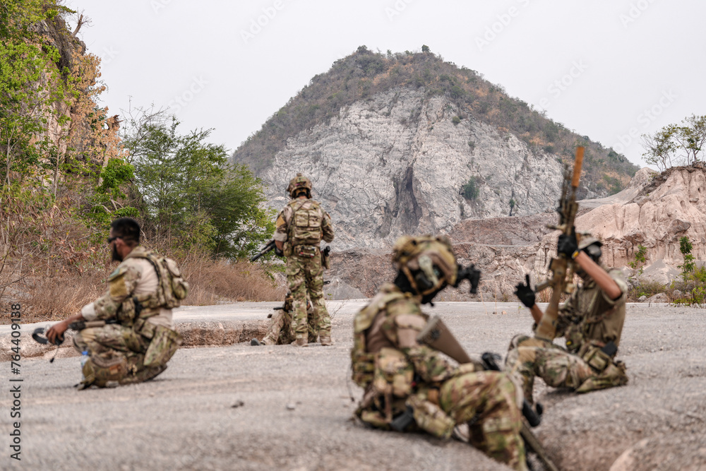 Soldiers in camo gear during a tactical operation with binoculars and rifles on a rocky terrain, showcasing military precision and readiness. Soldiers in camo gear during a tactical operation with binoculars and rifles on a rocky terrain, showcasing military precision and readiness.